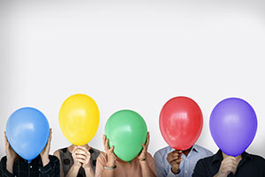People holding various colored balloons in front of their face